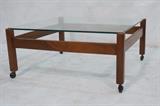 Lot 129:  Square Glass Top Rolling Coffee Table. Danish Modern Teak frame with inset glass top. : Dimensions:  H: 15 inches: W: 32 inches: D: 32 inches --- 