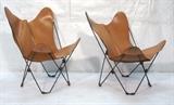 Lot 270:  Pr Butterfly Lounge Chairs. Tan leather sling on black iron frame. : Dimensions:  H: 34.5 inches: W: 26 inches: D: 28 inches --- 