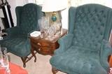 Two matching green deep tufted armchairs, end table and crystal.