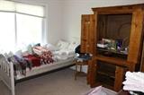 Twin bed, linens, decorative pillows and cushions. Antique pine armoire.