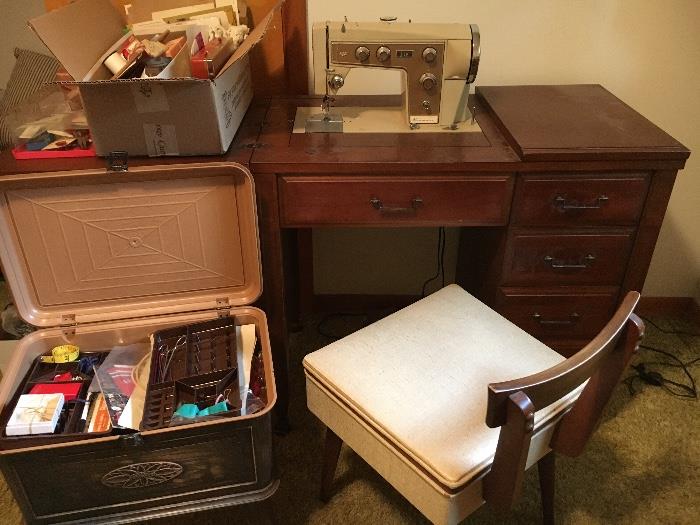 Vintage Kenmore sewing machine in cabinet with matching chair, assorted vintage sewing goods.