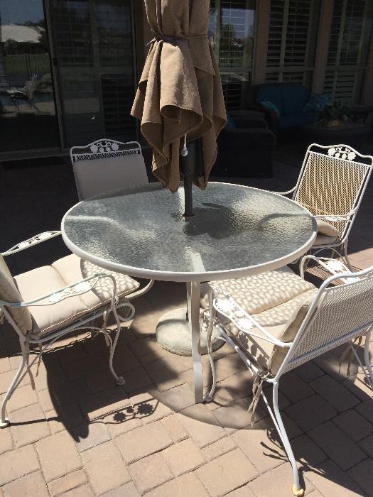 Round glass top patio table with 4 mesh chairs with cushions and umbrella