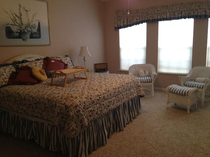 king bed with wicker headboard, chairs and footstool