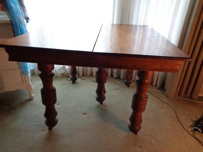 Antique oak dining room table on turned pedestal legs with casters.
