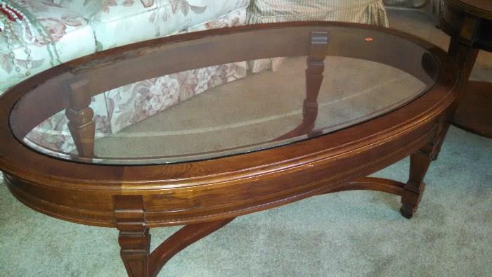 Walnut oval coffee table with glass top.