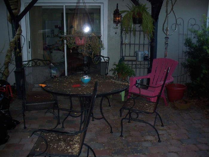 Patio table with 4 chairs, wrought iron Baker's rack, pink adirondack chair.