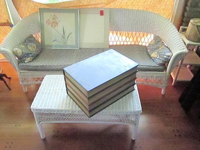 Wicker coffee table, sofa, art, and book style chest.