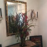 Impressive floral arrangement, striking black & gold mirror,  and matching wall sconces
