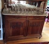 Detail of lower part of antique French sideboard/server - has two drawers & two doors with shelves inside. Note marble top & carved details on the doors. Plus lots of crystal stemware - see next photo for details.