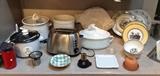 Small appliances including vintage red Braun coffee grinder, rice cooker, Rival CrockPot, Hamilton Beach stainless toaster, white Sur La Table utensil crock, Apilco Williams-Sonoma rooster casserole, Thora fish platter, Villeroy & Boch "Audun Chasse" & "Audun Ferme" plates & bowls, terra cotta garlic baker