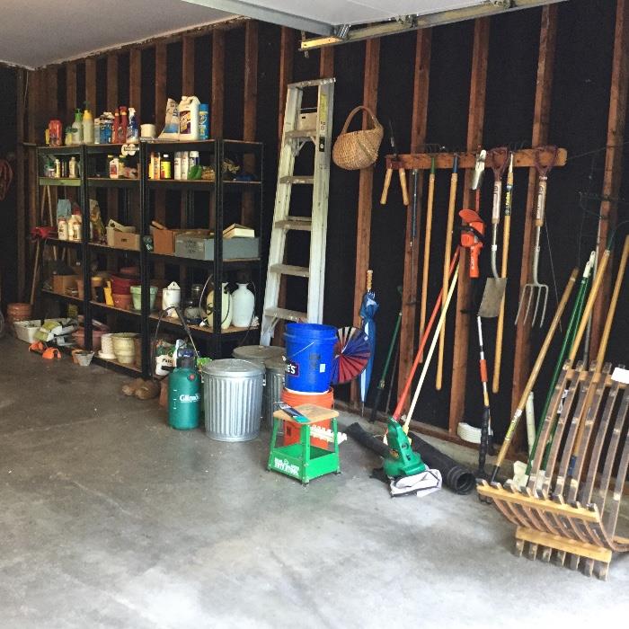 The garage is full of tools and  gardening supplies.