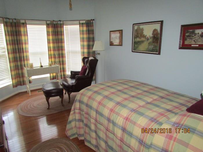 Leather chair and ottoman shown in guest room with coordinated linens and draperies