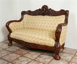 Lot 19: KARPEN CARVED ART NOUVEAU SETTEE: Attributed to Karpen or Tobey, frame carved overall with floral rose vine and art nouveau motifs. Crest with figural semi-nude maiden. Yellow floral upholstery. Overall measures 42'' h. x 59 3/4'' x 29 1/2''.