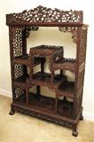 Lot 47: CARVED ORIENTAL ROSEWOOD ETAGERE: Carved openwork decoration all over, multi level open shelves, on paw feet. 62 3/4'' h. x 42 1/2'' x 16''.
CONDITION: Repair to trim at top, other wear consistent to age and use.