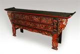 Lot 1010:  MASSIVE MONGOLIAN CARVED ALTAR TABLE: A large and richly carved red and black lacquer 4 drawer altar table. The top has upcurving ends with pierce carved wing support depicting Asian horsemen. The cabinet with four carved drawers over 5 carved panels. Approx. 8'9'' long x 45 1/2'' h. x 21 1/2''. Age unknown.