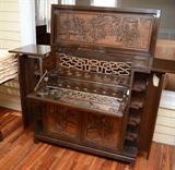 Lot 1205:  CARVED ORIENTAL LIFT TOP BAR: Carved panels front and sides featuring outdoor genre scenes. Lift top, 2 top doors open to reveal fall front with mirrored base interior, glass storage and carved decoration. 2 lower doors with slide out shelf with bottle storage. Corner side doors with shelves and stemware storage. 42 3/4'' h. x 44'' x 19''
CONDITION: Wear consistent with age and use.