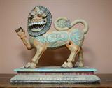 Lot 1077:  POLYCHROME CARVED TIBETAN TEMPLE LION: Carved wood lion with exaggerated mask with wood base. Polychrome paint decorated, age unknown. Overall 29'' h. x 30'' x 13 3/4''.
CONDITION: Loss of paint, drip of pink paint on base.