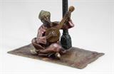 Lot 1135:  BERGMAN, Franz Xavier (1861-1936)ATTRIB: Austrian bronze orientalist figural lamp depicting man on a colorful rug, playing his mandolin. Bergman attribution, signed ''Austria''. The rug measures 6'' x 3 3/4'', the lamp 9 1/4'' from socket top to base.