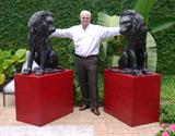 Lot 1151:  PR BRONZE PALACE GUARD LIONS ON STANDS: Full body lions on red painted wood pedestals The lions measure approx. 39'' tall x 30'' d x 23'' w. Pedestals measures approx. 30'' h. x 33'' l. x 21'' d.