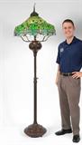 Lot 1229:  TIFFANY STYLE BRONZE & LEADED GLASS FLOOR LAMP: The shade in the dragonfly design. Measures approx. 7' tall, the shade 26'' diameter. Looking for a pair? View the next lot 1230.