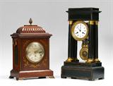 Lot 1150:  ENGLISH J.W. BENSON BRASS INLAY BRACKET CLOCK: Mahogany case with pineapple finial, brass foliate inlay on front. Silvered metal dial marked J. W. Benson Ltd., London. Single fusee time only movement marked with Benson and Ludate Hill address, serial number 11751. Overall 16'' h. x 10 1/2'' x 7''.
CONDITION: Streaking to dial, uneven finish to brass. Suspension spring in need of replacement, otherwise appears to currently be running once repaired, not guaranteed to continue. Replacement key to case, wind key and pendulum in office.

Lot 1142:  FRENCH BOULE INLAY PORTICO CLOCK: Ebonized black wood case with boule brass inlay decoration. French time and strike movement marked Broror? Brevete. Styled brass pendulum with star. 18 1/2'' h. x 9 3/4'' x 6''.
CONDITION: Missing trim, chips to case. Currently not running.