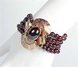 Lot 1018:  GOLD AND GARNET BRACELET: Four strand garnet bead bracelet of approximately 136 beads, 6.5 mm. totaling approx. 132 Ct. The large cabochon is bezel set in etched 10K yellow gold, the actual clasp is 14K (assayed). Length: 8 1/2'', Weight: 82.8 grams total.