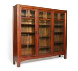 Lot 1042:  ARTS & CRAFTS OAK TRIPLE FRONT BOOKCASE: Three glass front doors, each section with adjustable shelves. Old label on back reads 515. 58'' h. x 63 1/4'' x 12''.
CONDITION: Wear consistent with age and use. Peeling to back panel.