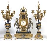 Lot 1069:  3 PIECE IMPERIAL FIGURAL CLOCK GARNITURE SET: Ornate case with figural pan children holding rope with floral swag standing on enamel over cast base. Porcelain dial marked Imperial, Made in Italy. Key wind time and strike movement. Measures 24 1/4'' h. x 13 1/4'' x 8''. Sold with matching candelabra garniture, measures 26 3/4'' h. x 11''.
CONDITION: Condition issues exist especially to garniture set. Please call for condition.