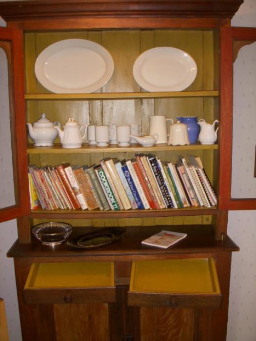 Note the mustard paint inside.  Cupboard displays some white ironstone, and a shelf of cookbooks