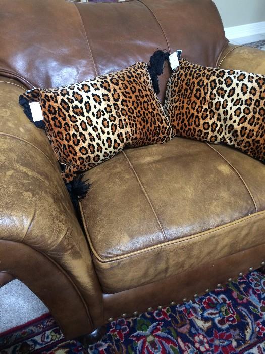 One of two leather over-stuffed chairs; some of the decorative pillows