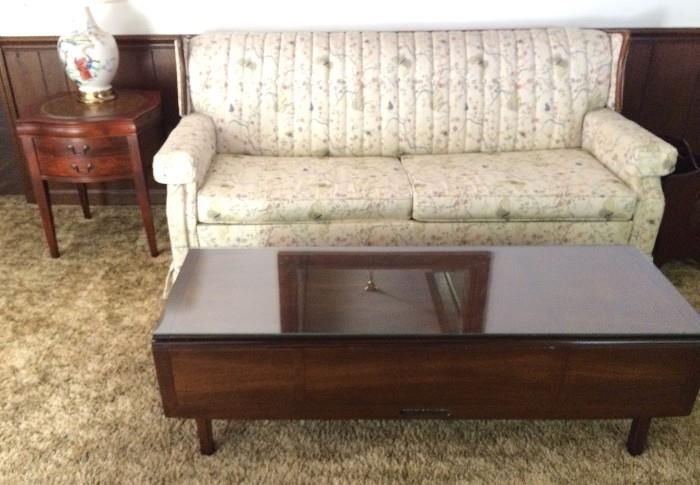 Petite vintage sleeper loveseat with butterfly-embroidered upholstery; lovely antique drop-leaf coffee table with glass top; leather-top drum side table with drawers