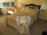 Full sized bed w/antique oak headboard; pair of white side tables, upholstered armchair, bedding