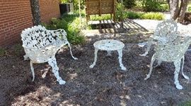 Cast iron patio set including love seat, arm chair, chair, and table.