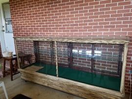 Large display case sitting on dolly. Case is from The Hat Shoppe in Hawkinsville, GA. Bag from The Hat Shoppe is displayed inside case. 