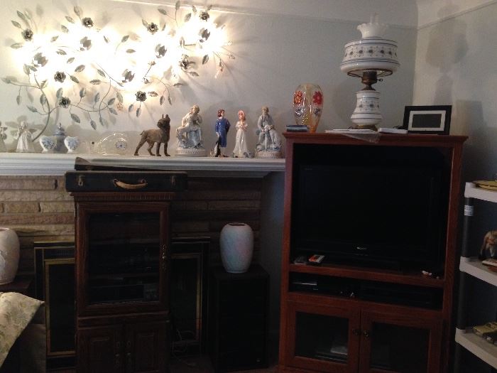 Note the hurricane lamp, it has a matching hanging one too!  The entertainment center has a flat screen Sony T.V.! Small figurines adorn the mantle and large heavy cast iron Terrier dog possibly by Hubley is illuminated by the beautiful leaf wall hanging.