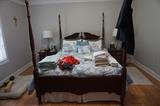 Blue and white comforter. Bed frame with posts. Two matching night stands. 