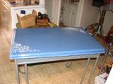 This little breakfast table has a blue enamel top with white flowers at two of the corners. It has pull out leaves on each side. The support mechanism on one of the leaves needs to be restored but the rest of the table is in good shape.