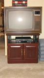 The RCA television sits atop a Colonial-style faux-cherry finished cabinet that has storage at the bottom and brass pulls.