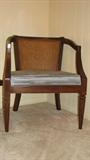 This photograph displays one of two matching barrel chairs with light blue upholstery on the cushion and cane back inset.  We feel the wood is likely to be dark-stained walnut.