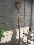 The rustic bird house has two perches, a small metal bowl for a bird bath or for birds and other animals to get a quick drink of water, and is free-standing with its heavy circular metal base, making it a convenient addition to your yard or patio.