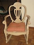 This beautiful rocker is painted an antique white and has an apricot-colored pillow in the seat.