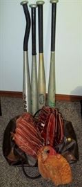 Base ball gloves and bats with bag and a softball 