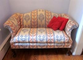 Two vintage camel back love seats, with curved Mahogany legs. Solid construction.
