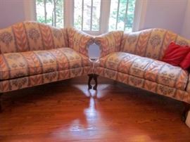 Two vintage camel back love seats, with curved Mahogany legs. Solid construction.