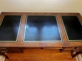 High-quality desk by Sligh.  Three tooled leather inlays, 5 drawers, brass drawer pulls.  One spot of damage to leather.
