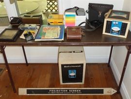 Several cameras, including a Polaroid, Bell & Howell Projection Scree, Light Bar & Projector