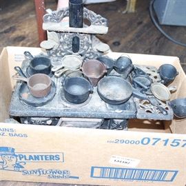 Miniature iron stove with assorted pots, pans and additional items