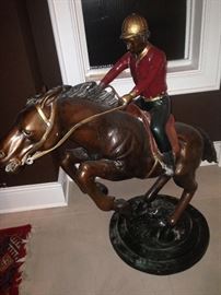 A three-dimensional, painted
bronze sculpture of a jockey in
red and green atop galloping
brown horse on its hind legs
on a circular base. 
The piece is 36 inches high
and 36 inches wide and 18.75
inches deep and weighs
roughly 80 pounds.