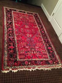 A rectangular, polychromatic,
geometric and floral patterned
wool Persian rug with shades
of blue, pink, green, yellow,
orange and white on a mostly
red background. The piece is 95 inches long and 55.5 inches wide
and has roughly 182 knots per square inch.