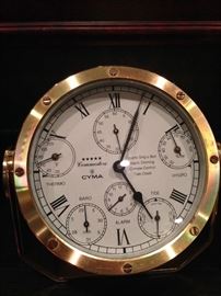 A 1960s-era Cyma Commodore
captain’s clock with circular
face, cylindrical body, a white
face with black Roman
numerals, and dials for
temperature, barometric
pressure, tide, hydrological
cycles, alarm and seconds. The
piece is 7 inches high, 6 inches
wide and 6 inches deep.